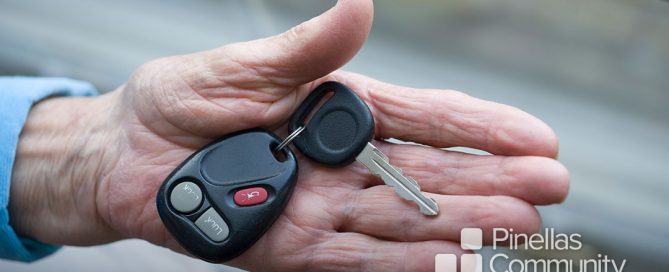 Close up of older adult&rsquo;s hand offering car key.