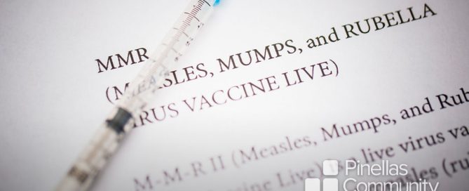 Syringe laying on MMR vaccine information sheet.