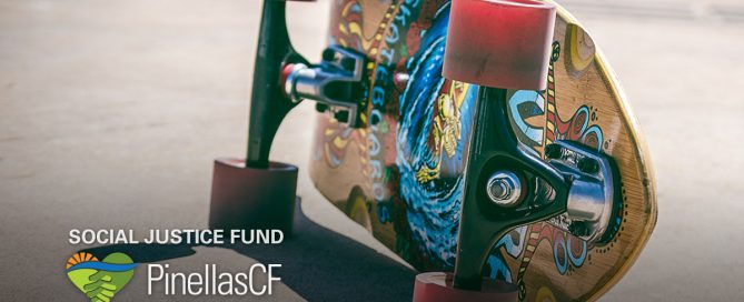 Closeup of a skateboard on the pavement on its side showing the artwork underneath.