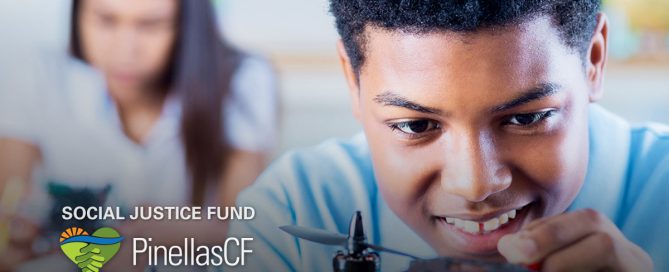 A teenage Black boy smiles as he works on a drone in the YDI Drone Club supported by PCF's Social Justice Fund.