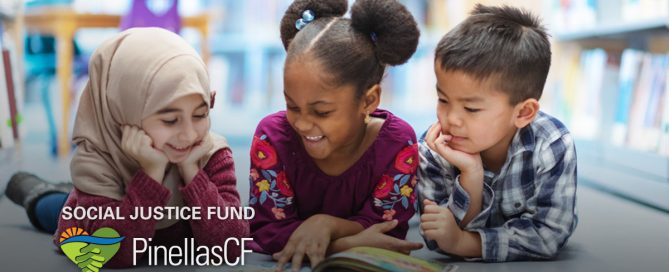 Three children reading books on library floor.