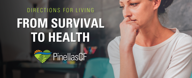 A troubled looking woman sits alone on a couch.