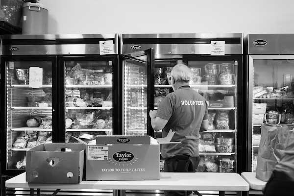 A volunteer at a food pantry stocking the refrigerator with food purchased with help of the Tampa Bay Resiliency Fund.