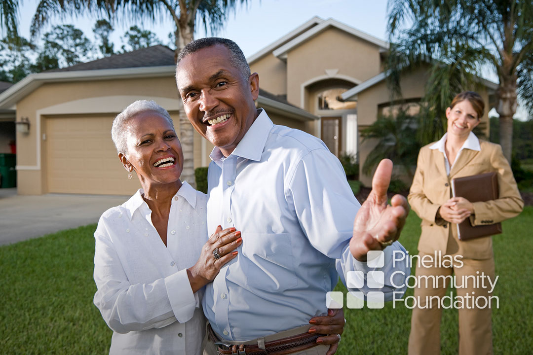 Older adult, happy couple in front of new home with their realtor.