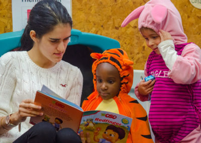 Preschool teacher reads to two students in costumes.