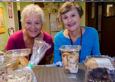 Two senior women enjoy volunteering at RCS Food Bank.