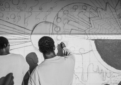 Black and white photo of volunteers sketching the mural on the wall.